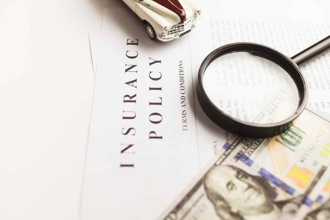 Insurance paperwork and documents on a desk with a house model, representing insurance claims after foreclosure